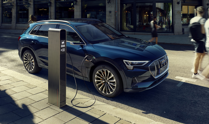 An Audi vehicle parked on a city street charging.