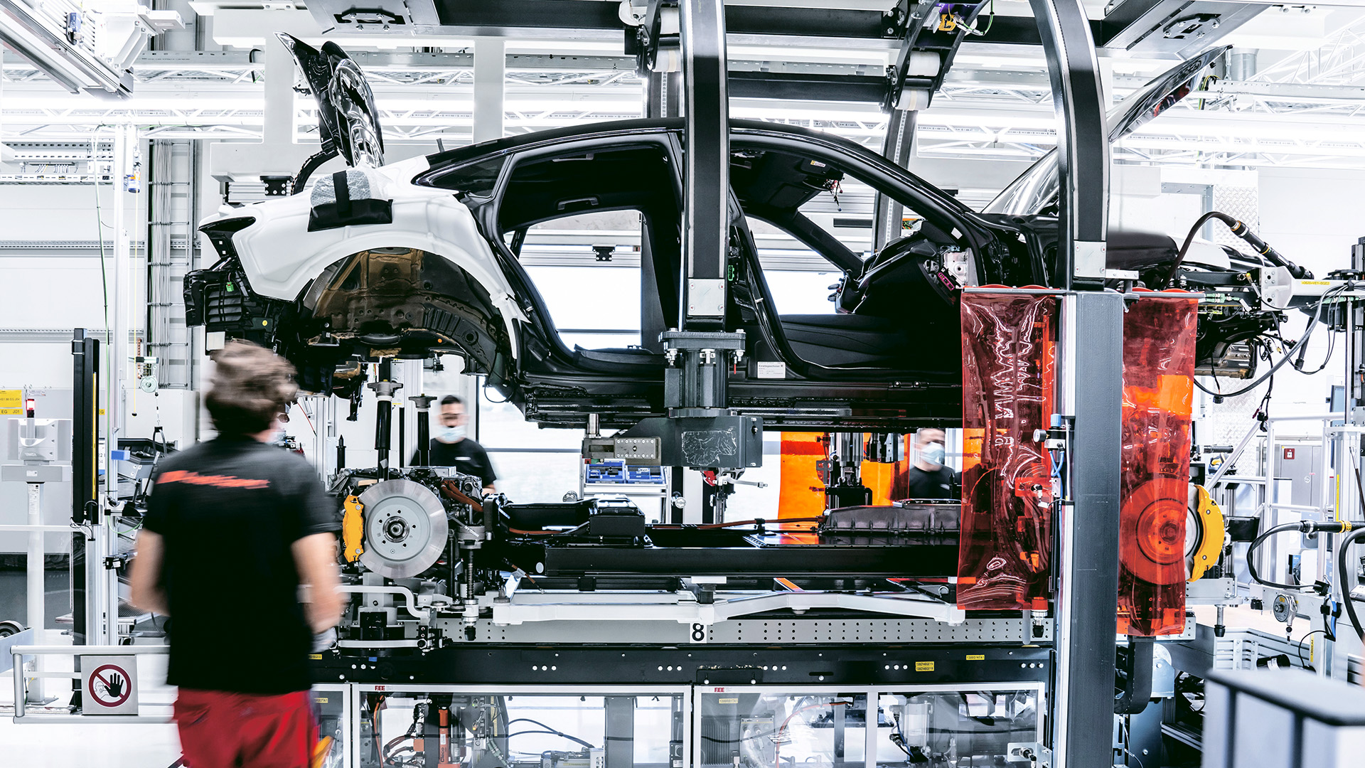 Deux techniciens Audi assemblent la carrosserie, la batterie, les moteurs électriques et la suspension de l’Audi e-tron GT dans l’usine de production.